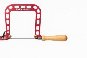 High-resolution image of the Knew Concepts 5-inch Mk.III fret saw featuring its red aluminum open-frame design, brass blade clamps, tension lever, and wooden handle on a plain white background.