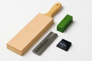 Leather strop with polishing compound next to a sharpened chisel on a wood bench